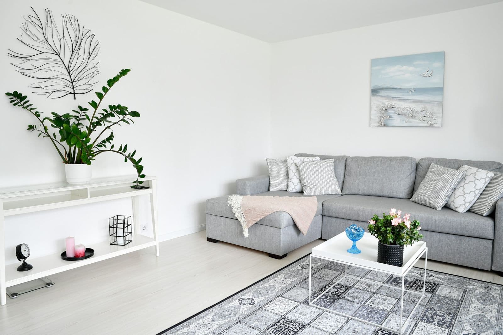 Ett ljust vardagsrum med en grå soffa och gröna växter